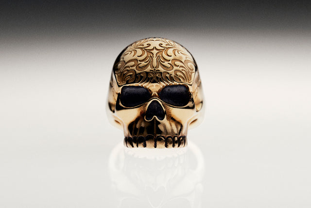 Tattoo Skull Ring in gold on a black and white reflective background
